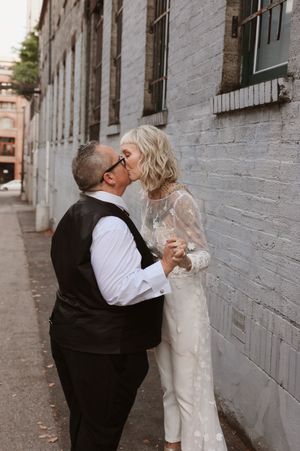 A romantic couple shares tender moments against a gray brick wall in a series of four connected photos.