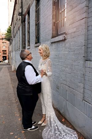 Bride and groom share intimate moments against an industrial brick wall backdrop.