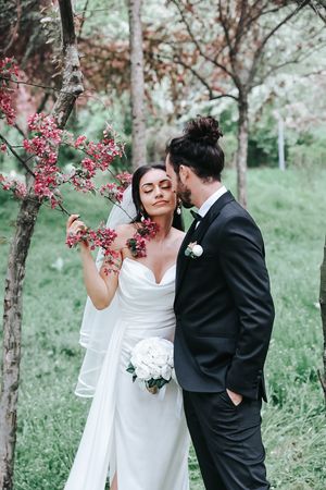 Spring wedding moment captured among blooming cherry blossoms in soft natural light.