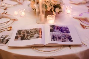 Wedding guest book displaying vintage black and white photographs with candlelight on a round table.