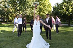 A joyful celebration on a grassy lawn during an outdoor wedding ceremony with the couple raising hands.
