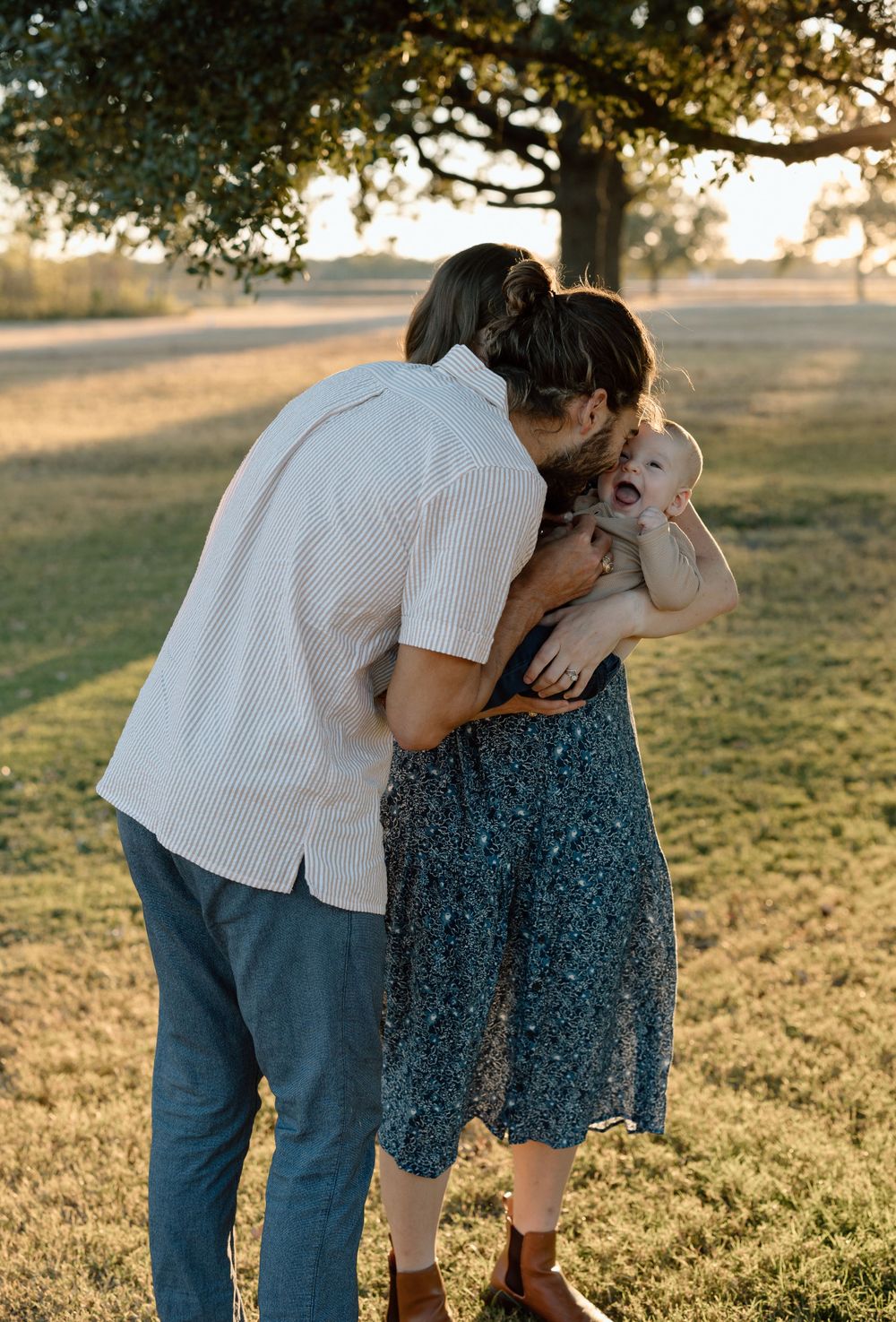 A tender moment between a couple during sunset in a grassy field.