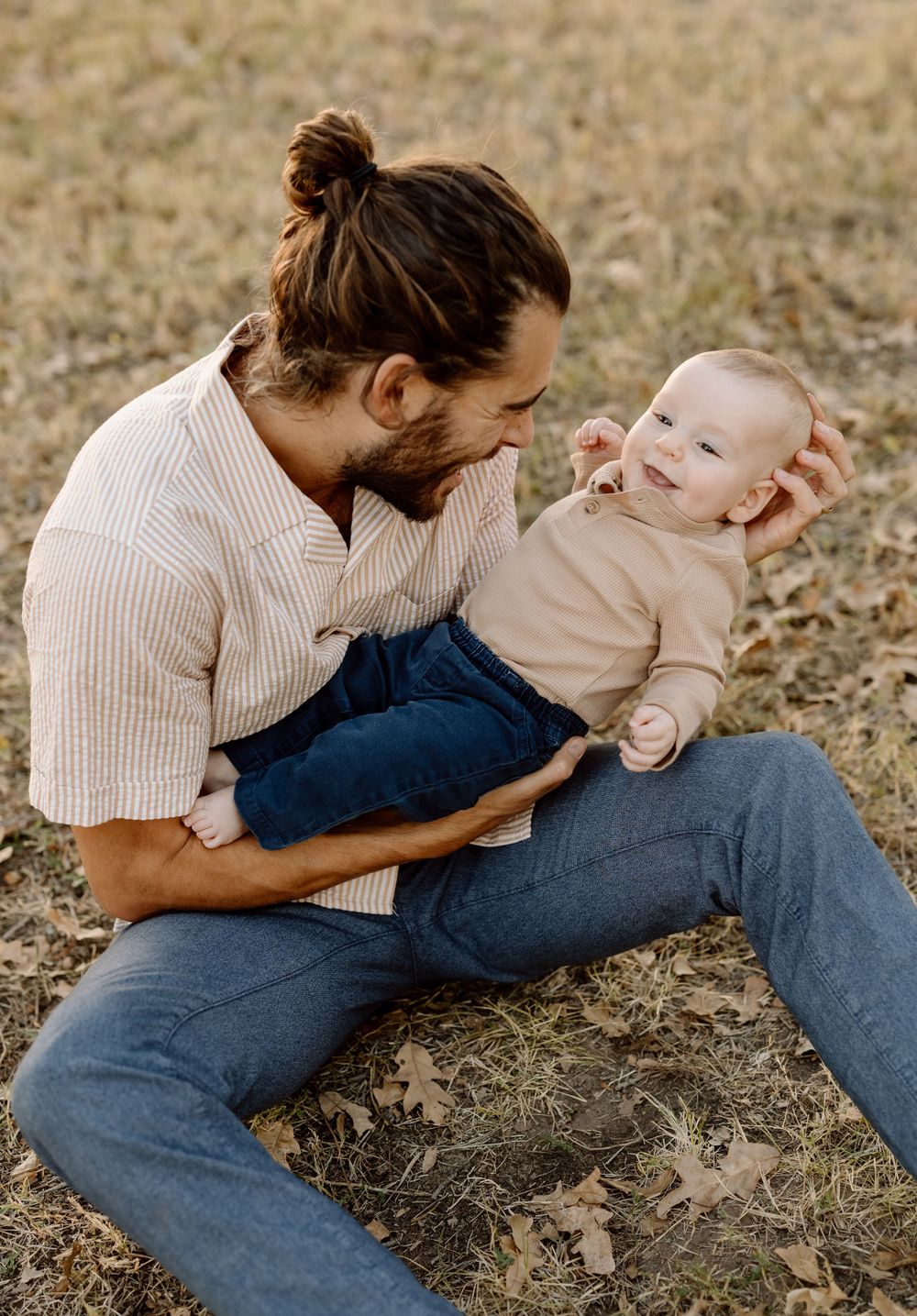 Dad sitting on grass holding baby
