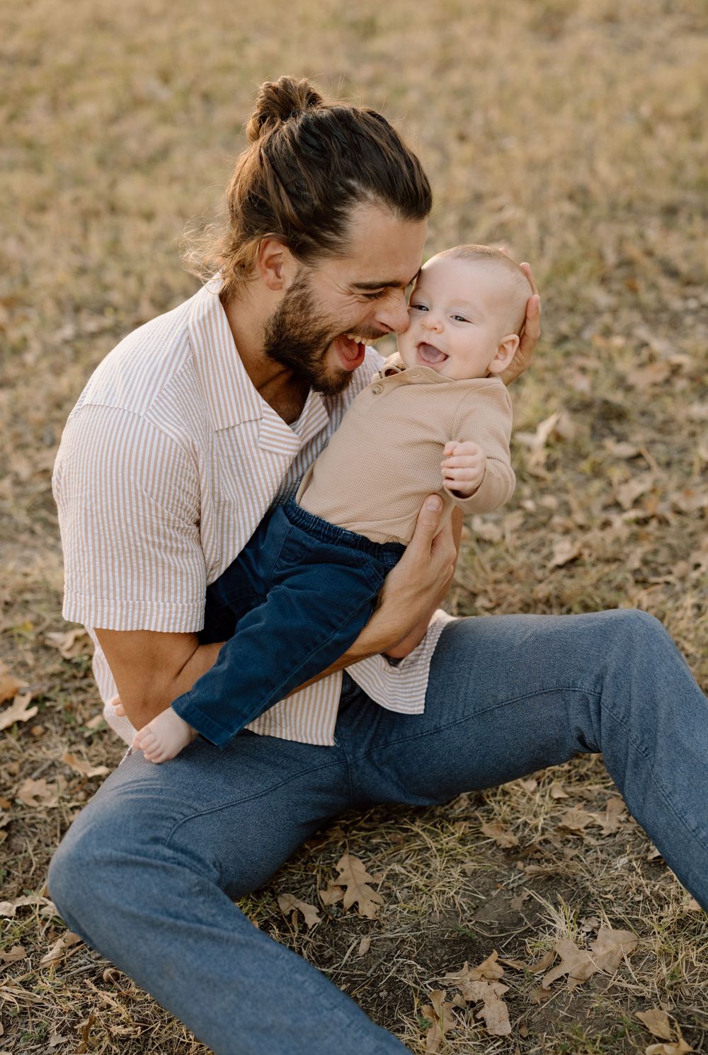 dad holding baby while sitting on grass