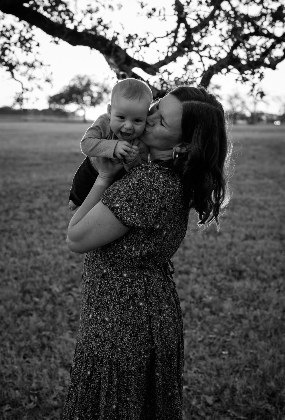 Black and white photo of mom holding baby standing outdoors