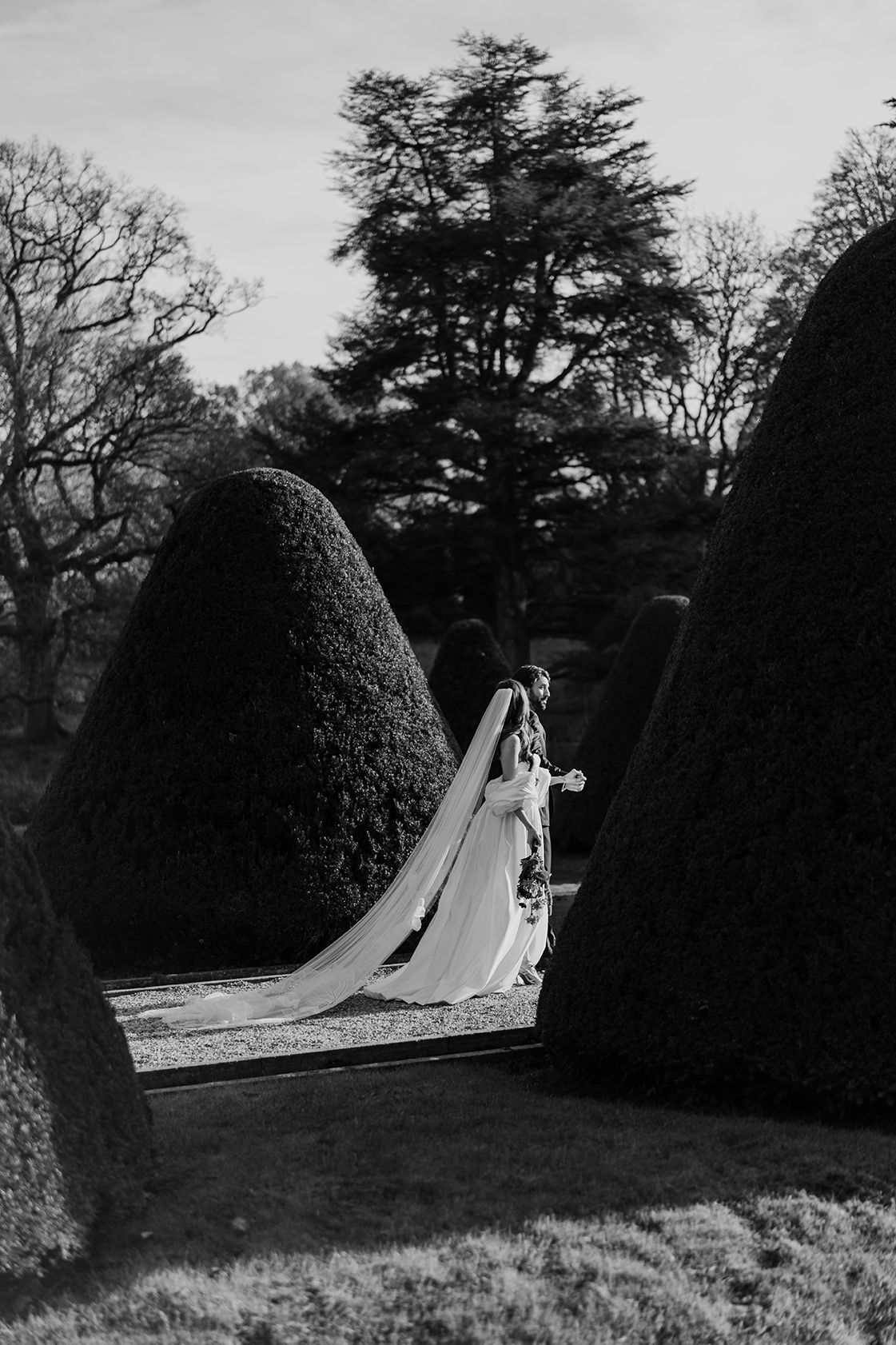 Bride and groom walking amongst trees at Middleton Lodge in black and white.