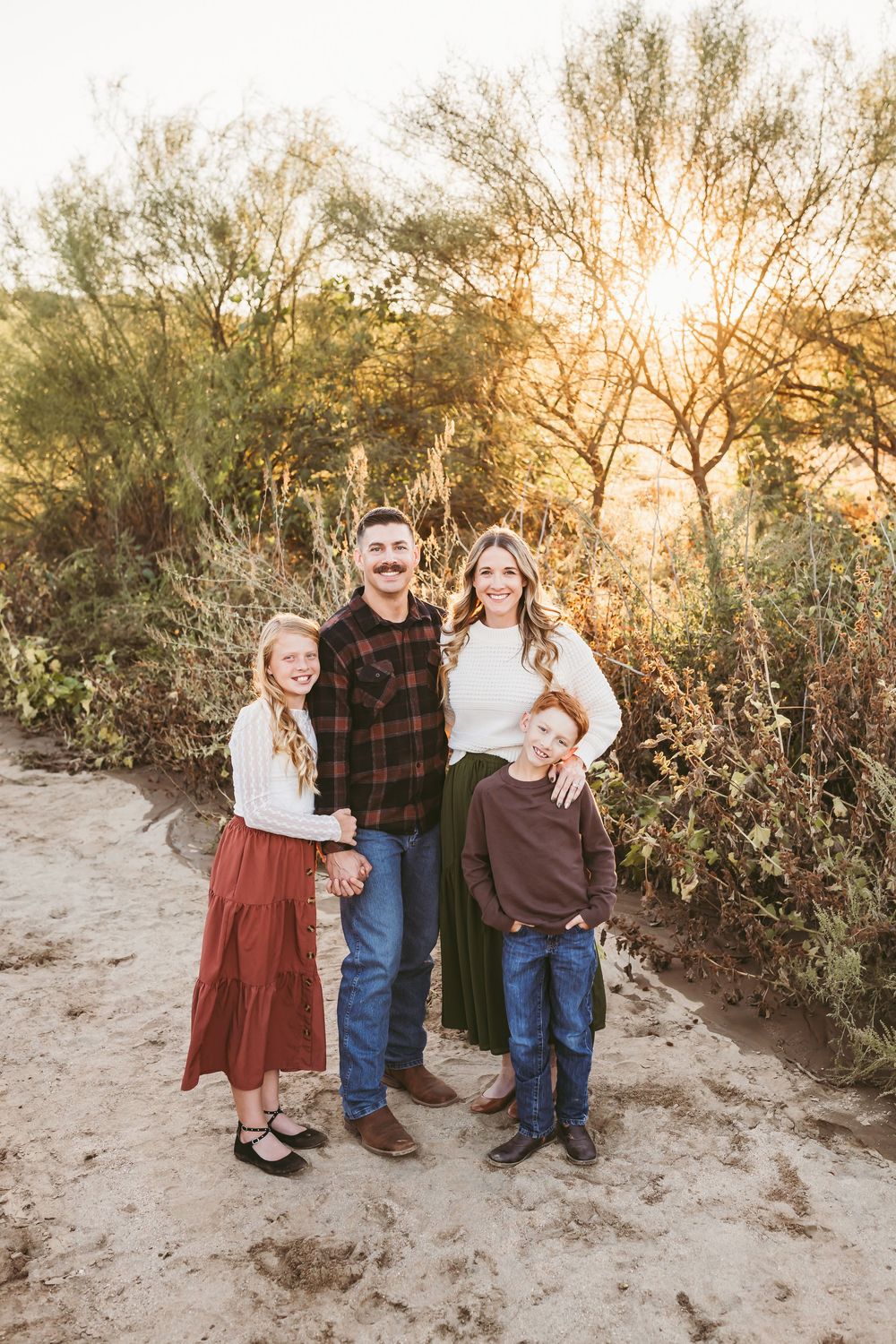 Family of four smiling outdoors at golden hour with family photographer heidi grace photography