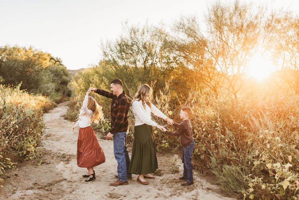 Family of four holding hands and dancing during their fall family session with beaumont family photographer heidi grace photography