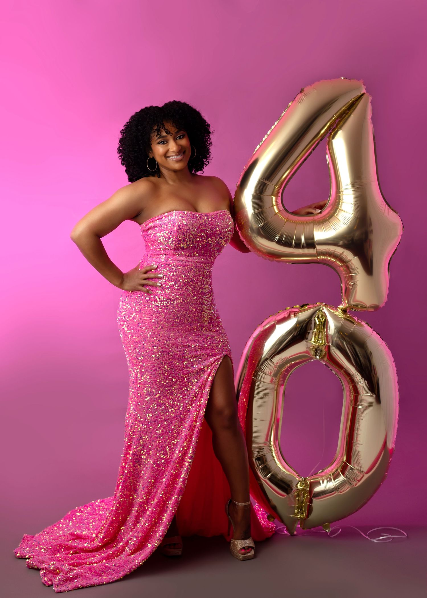 Glamorous portrait with pink tulle dress and crown while holding champagne glass.