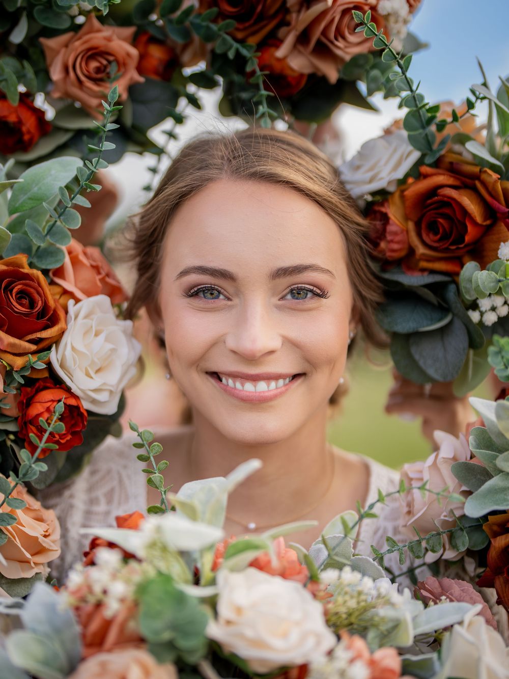 Beautiful wedding bouquet with coral and white roses, eucalyptus greenery, and baby's breath arranged in a circular frame.