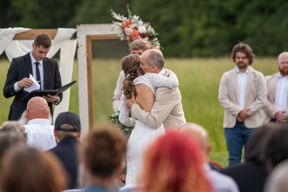 Wedding guests gather at an outdoor venue while couples dance and celebrate the special day together.