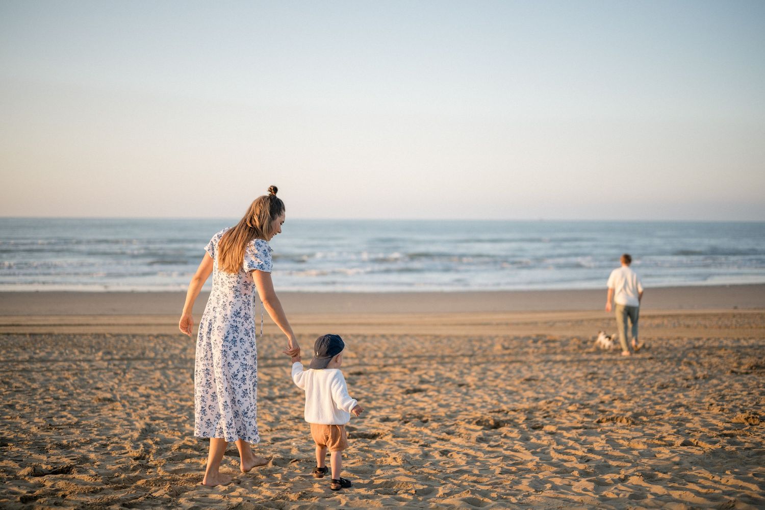A peaceful scene of people walking on a sandy beach at sunset.