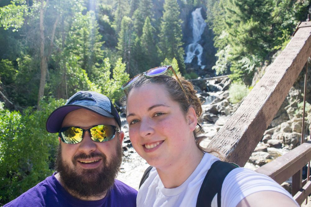 A waterfall cascades down a forested mountain slope in the background of this outdoor scene.