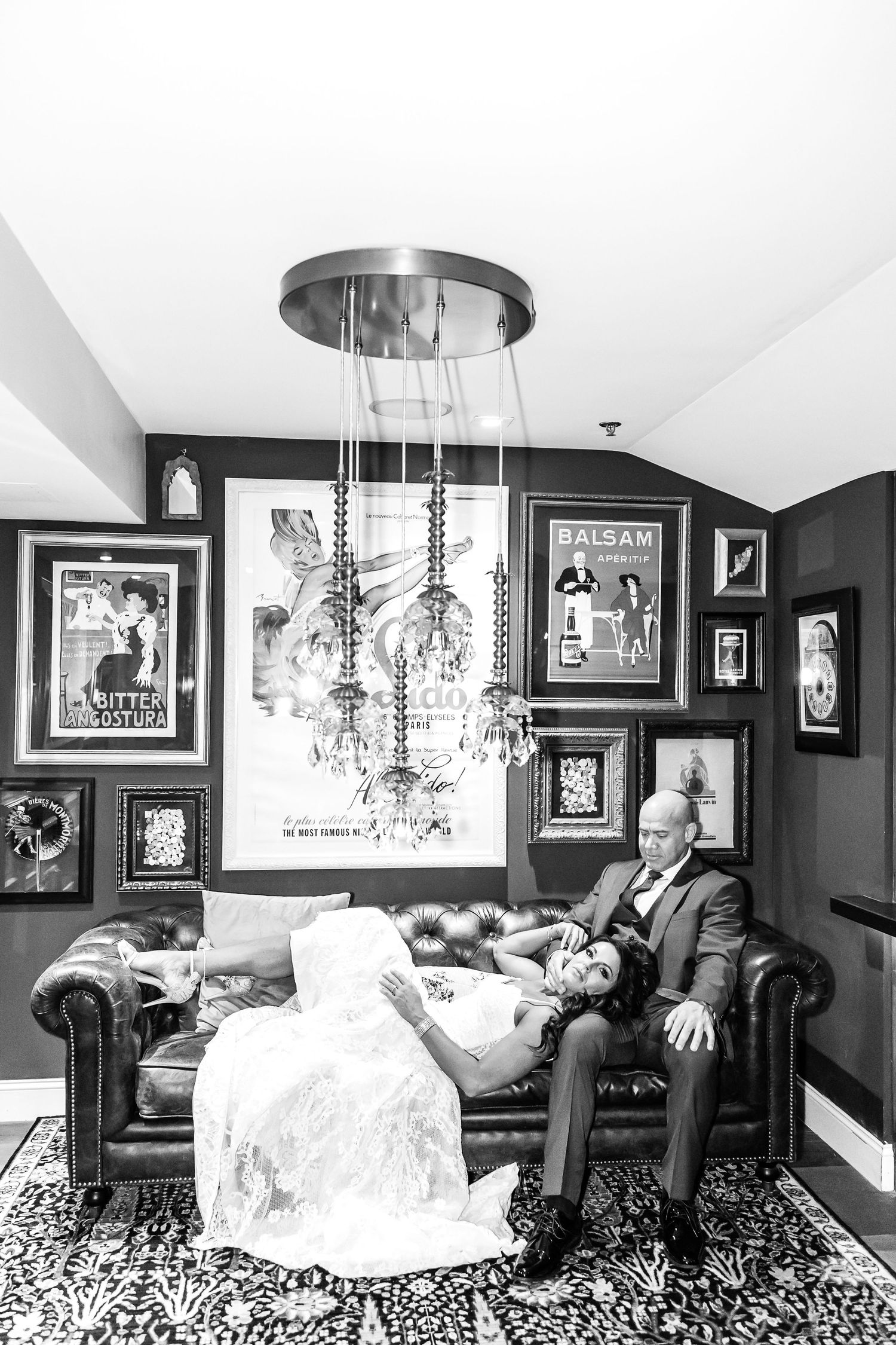 Artistic black and white photo series showing a couple lounging in an elegant room with crystal chandeliers and framed artwork.