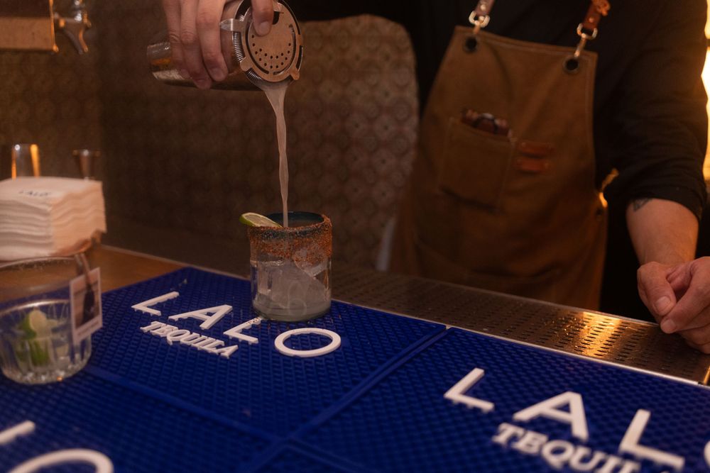 A close-up view of a blue bar mat with 'LALO' branding visible in a dimly lit restaurant setting.