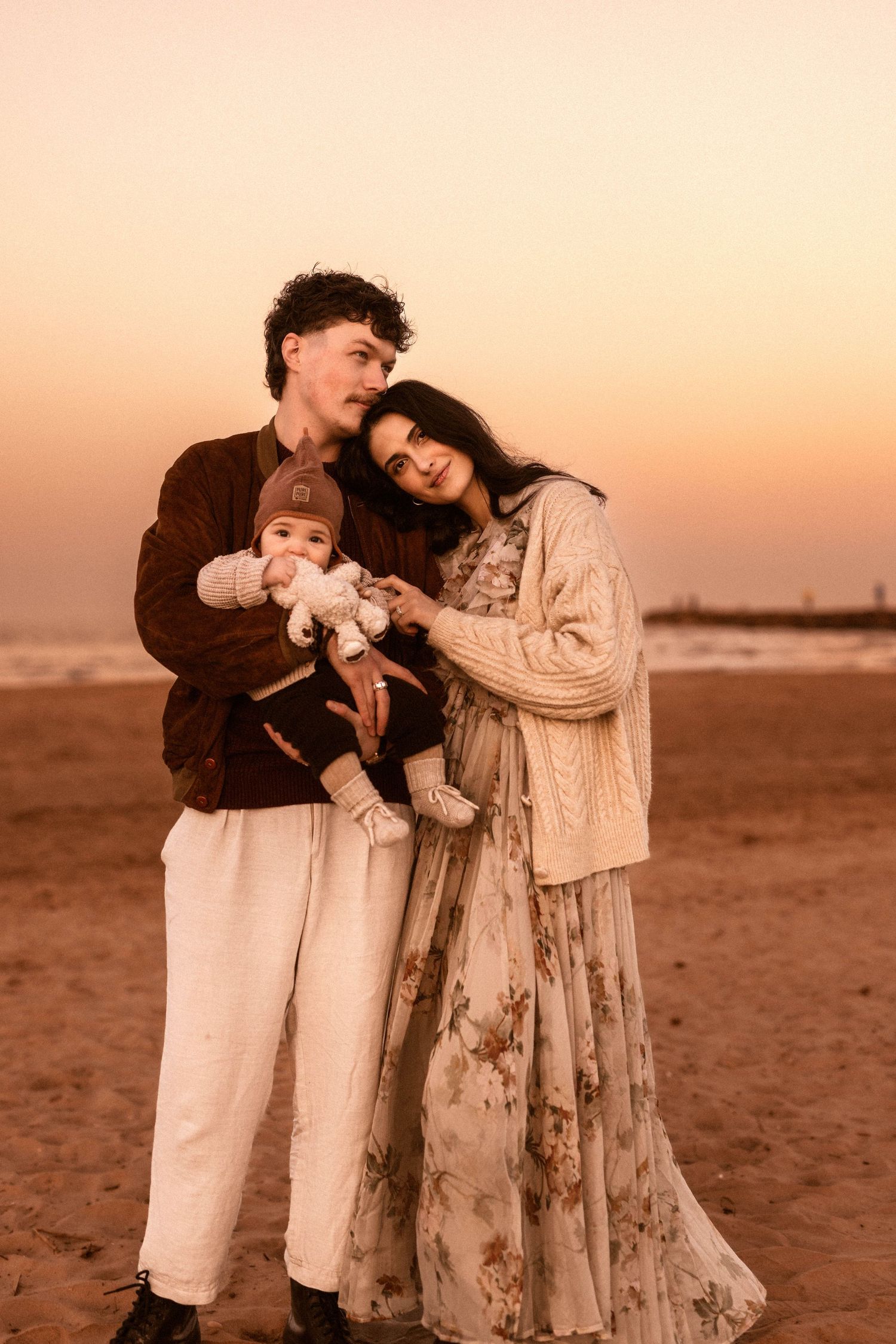 A couple shares a joyful moment together on a sandy beach during sunset for a family session with a photographer in Javea