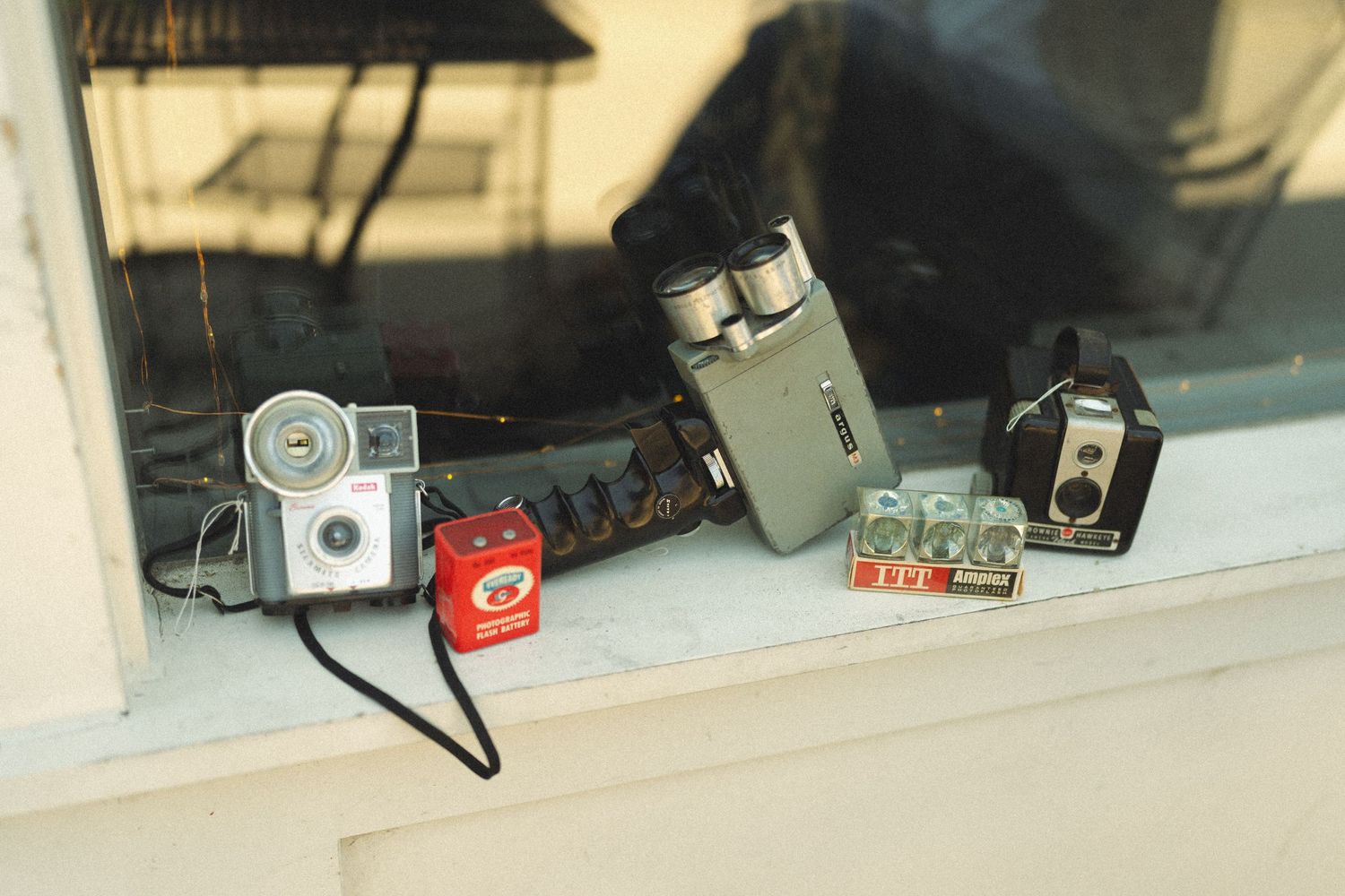 Collection of vintage cameras and photography equipment displayed on a windowsill.