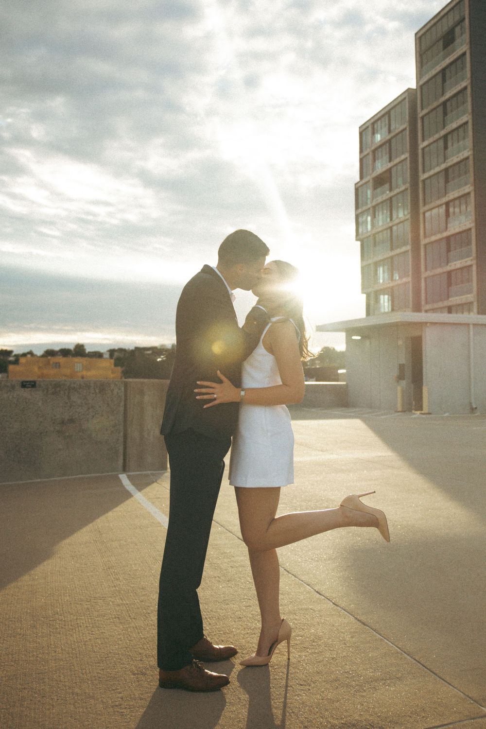 Romantic sunset silhouette of couple embracing on urban rooftop.