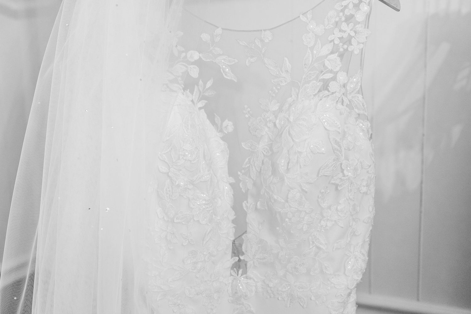 Delicate lace details on white wedding dress fabric with intricate floral patterns.