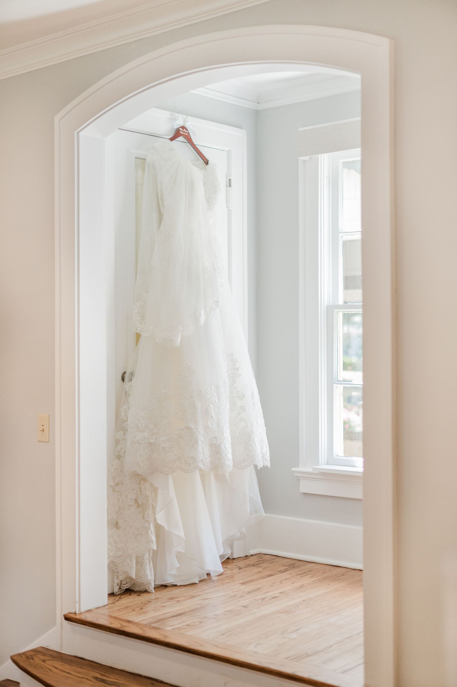 Wedding gown hangs in window ahead of a catholic wedding at Parish of Christ the King in Tulsa, OK.