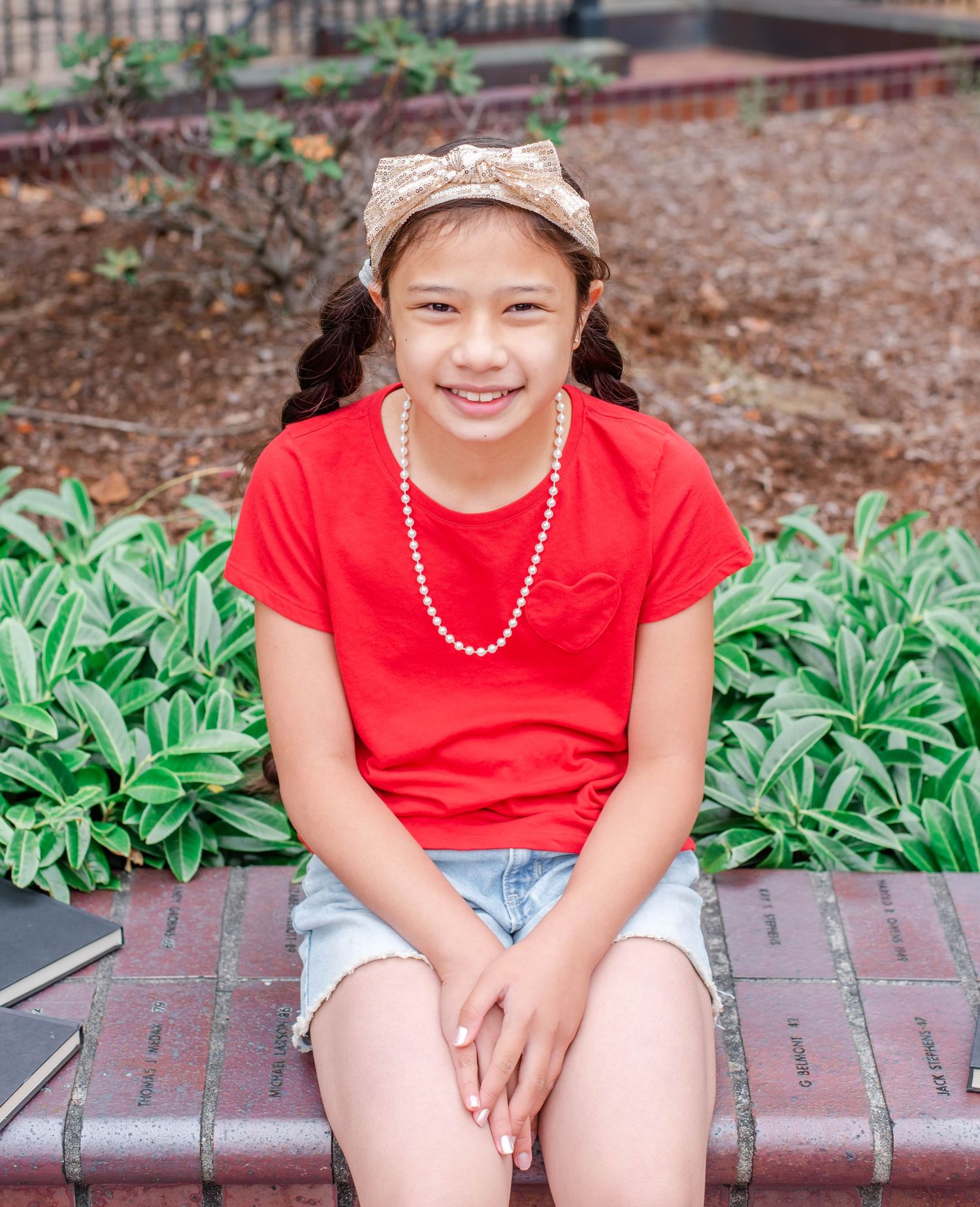 Casual outdoor portraits on brick seating area with greenery in background.