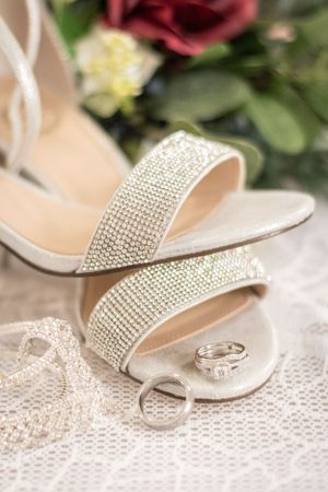 A close up shot of a bride's shoes and flowers with the couple's rings in focus.