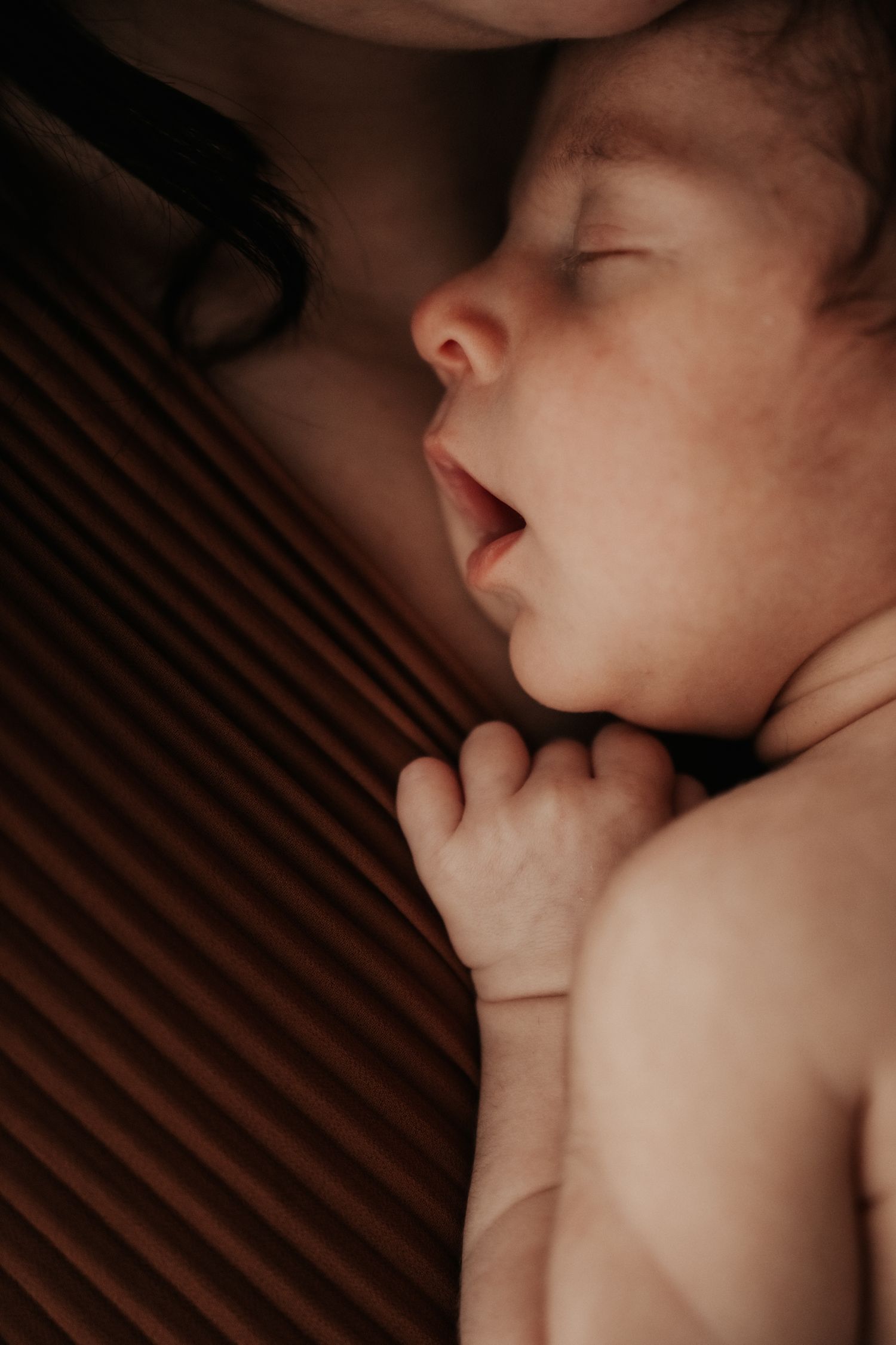 A tender moment between parent and sleeping baby in warm lighting.