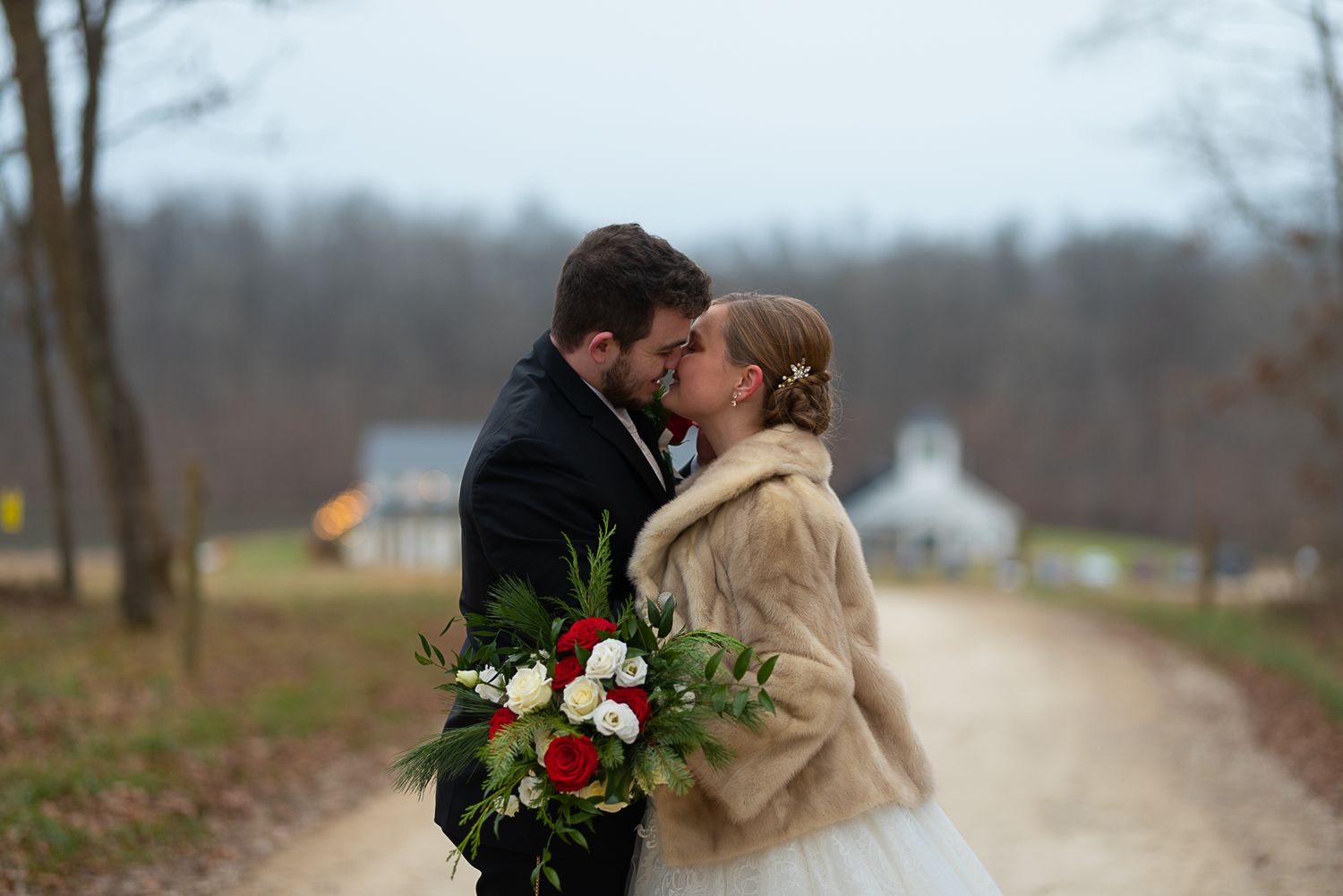 Couple shares romantic moment on country road holding winter bouquet.