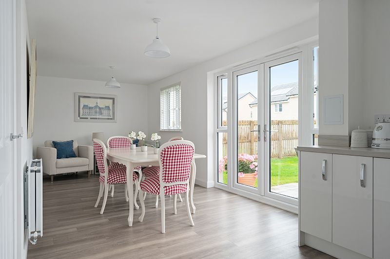 Modern white kitchen interior with panoramic windows and pink gingham dining chairs in a bright minimalist space.