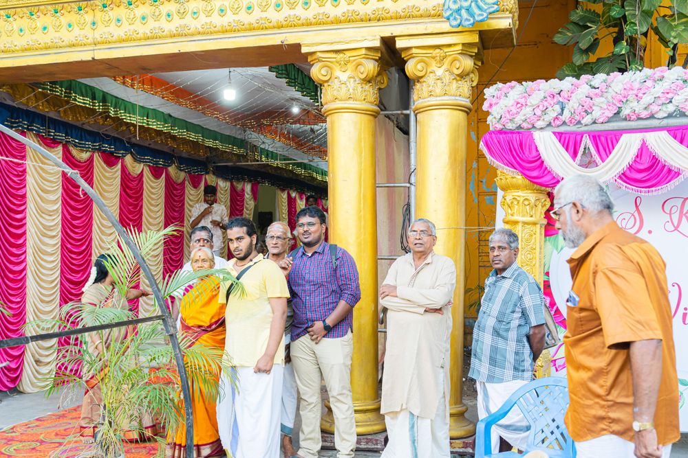 Decorated wedding venue with golden pillars and pink drapery showing guests gathered for celebration.