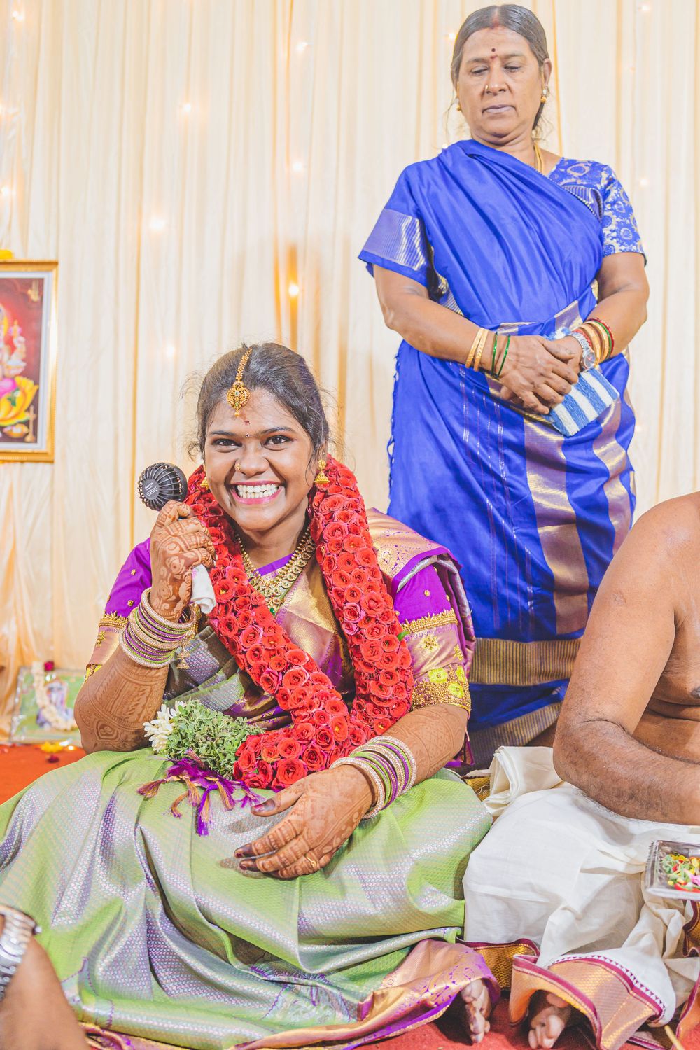 Traditional Indian ceremony showing women in colorful saris with floral garlands during a celebratory ritual.