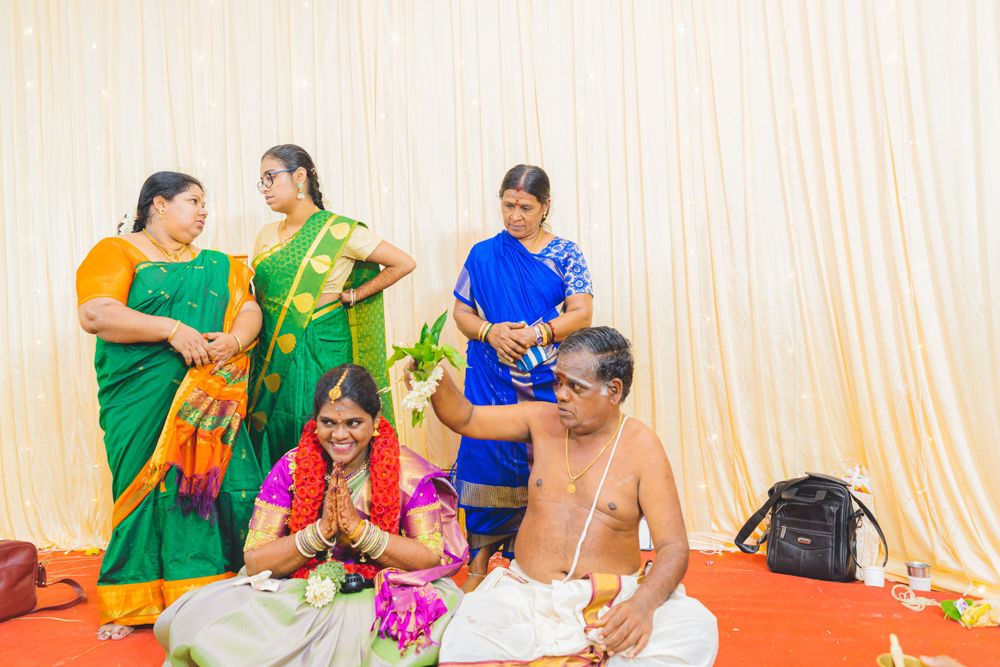 Traditional Hindu ceremony with attendees in colorful saris performing rituals on floor.