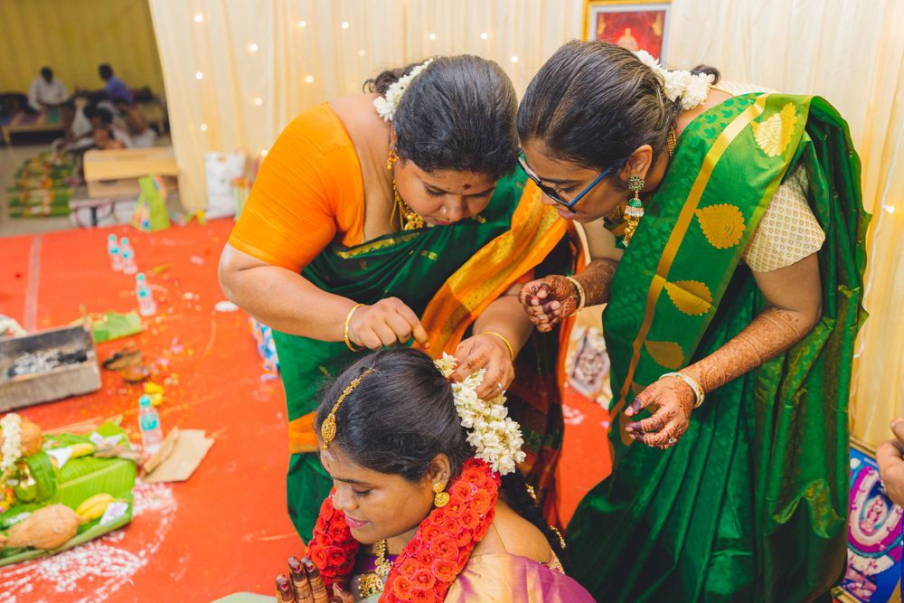 Women in vibrant green and orange saris performing ceremonial rituals during traditional celebration.