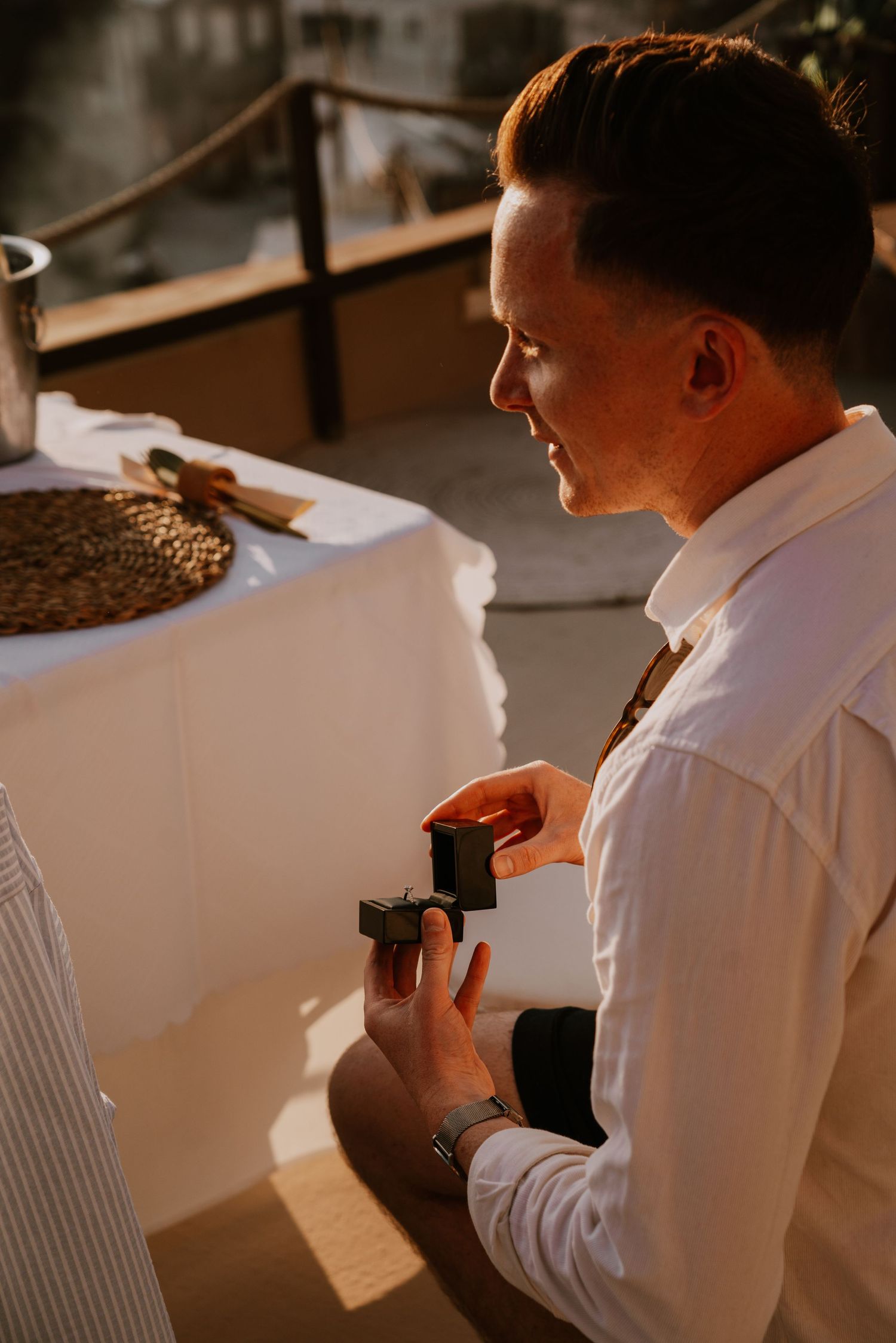 Person in white shirt examining small box in indoor setting.