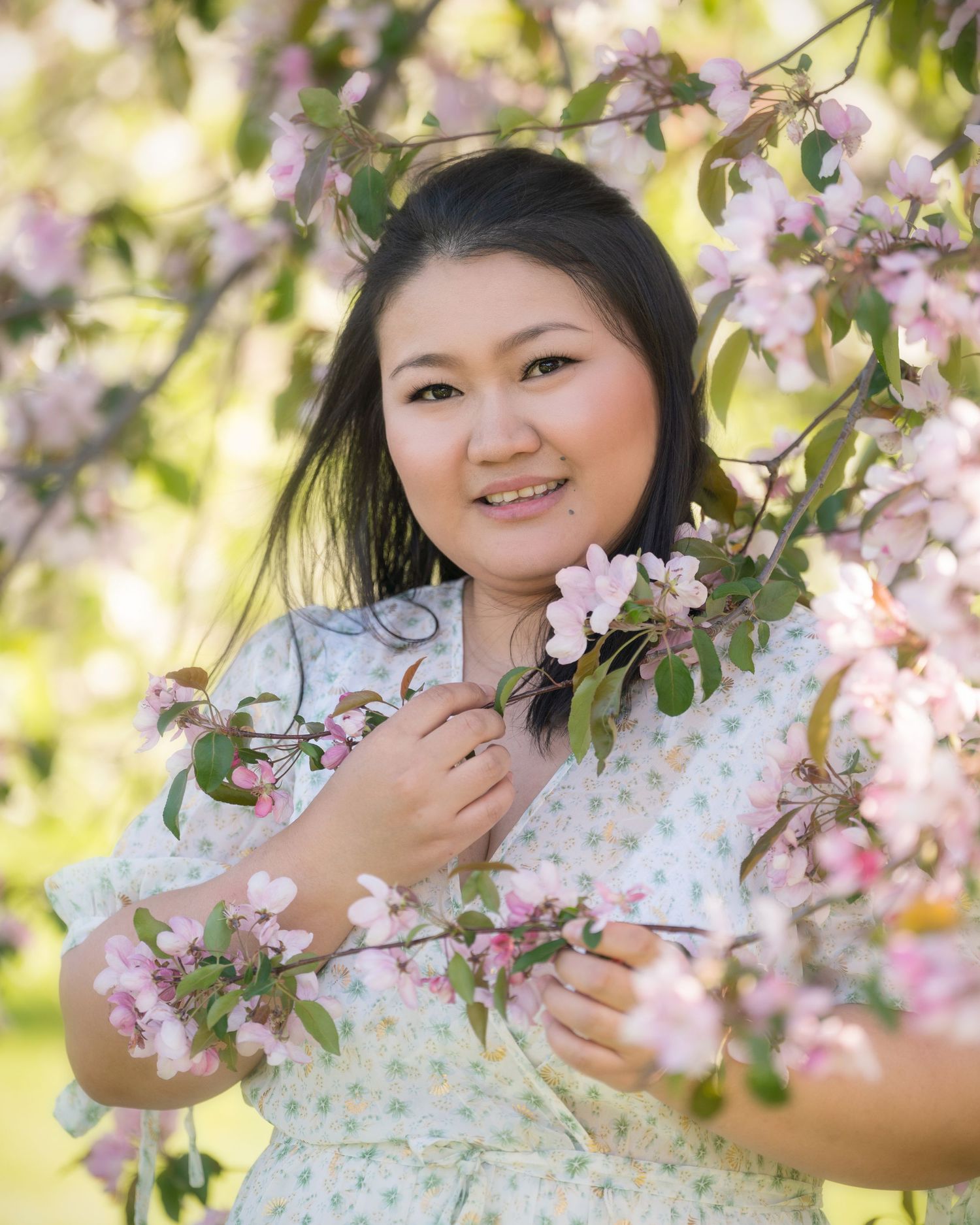 Spring portrait surrounded by delicate cherry blossoms and soft natural lighting.