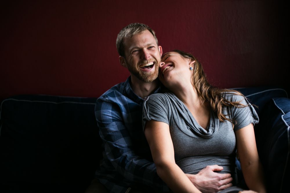 Intimate indoor photography session with dramatic lighting against dark background.