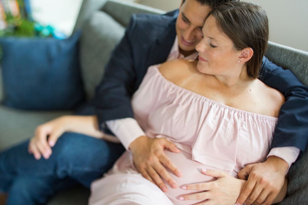 Tender indoor photography session with soft window light and casual setting.