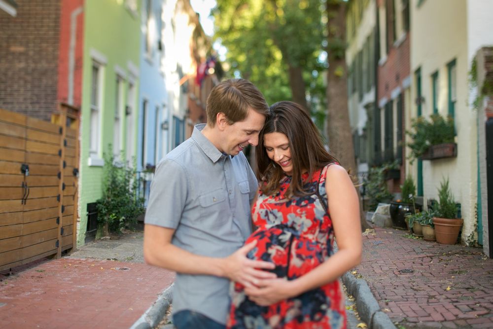A couple poses together on a brick-lined walkway surrounded by buildings.