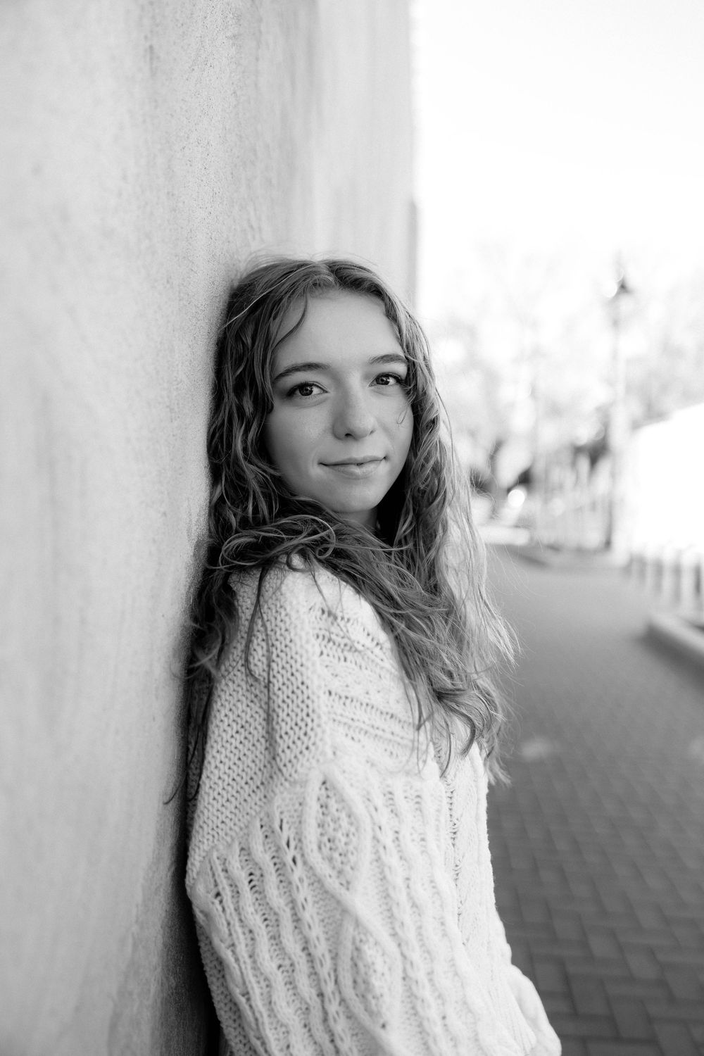 Black and white portrait series against a white wall with natural window lighting.
