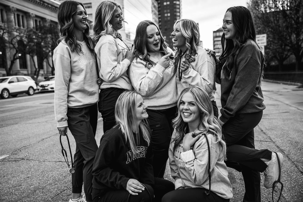 A candid black and white photo of a group gathered on a city street corner sharing a joyful moment together.