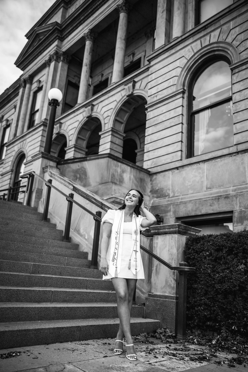 Black and white architectural photo showing someone posing on the steps of a grand historic building with columns.