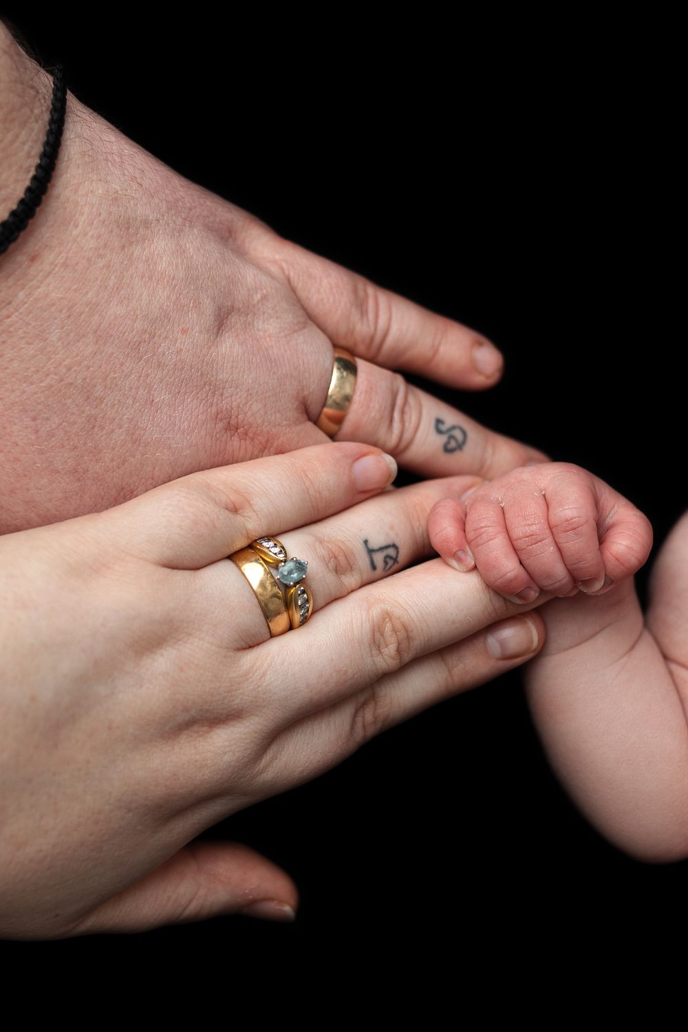 Close-up sequence of hands holding each other with gold rings against black background.