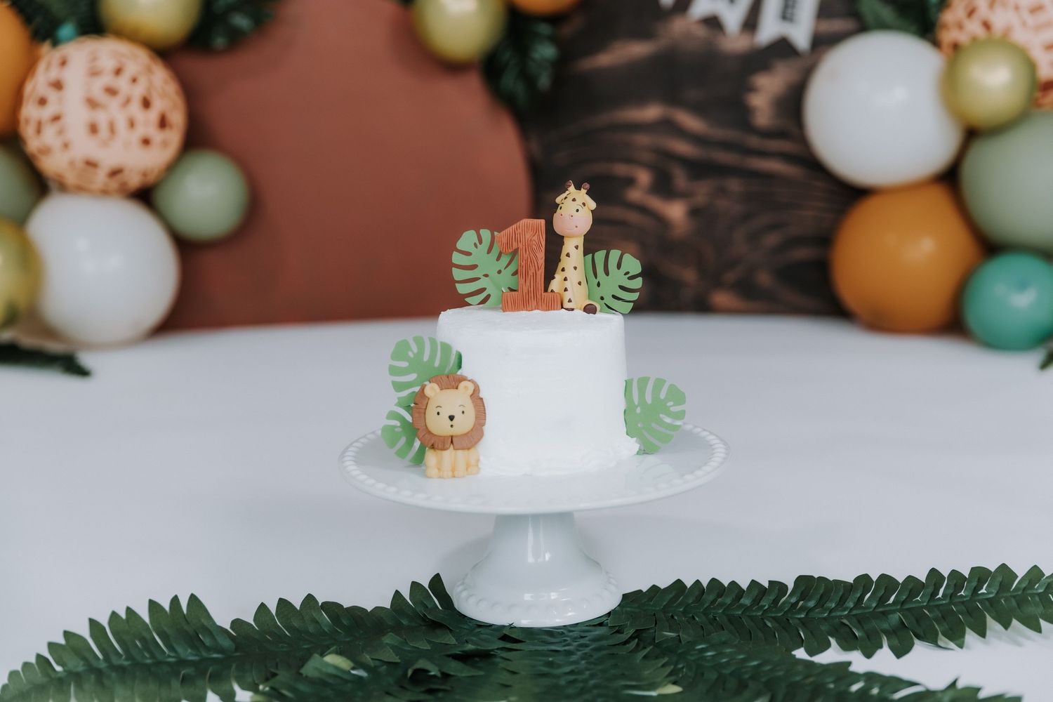 Safari themed cake display with green and orange balloon decorations.