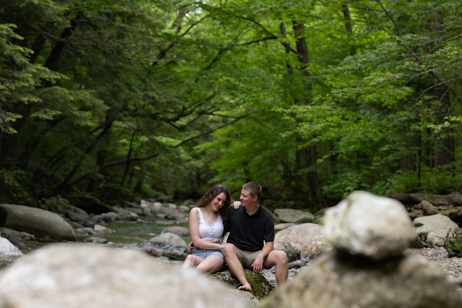 A romantic couple shares a tender kiss in a lush outdoor setting during their wedding photoshoot.
