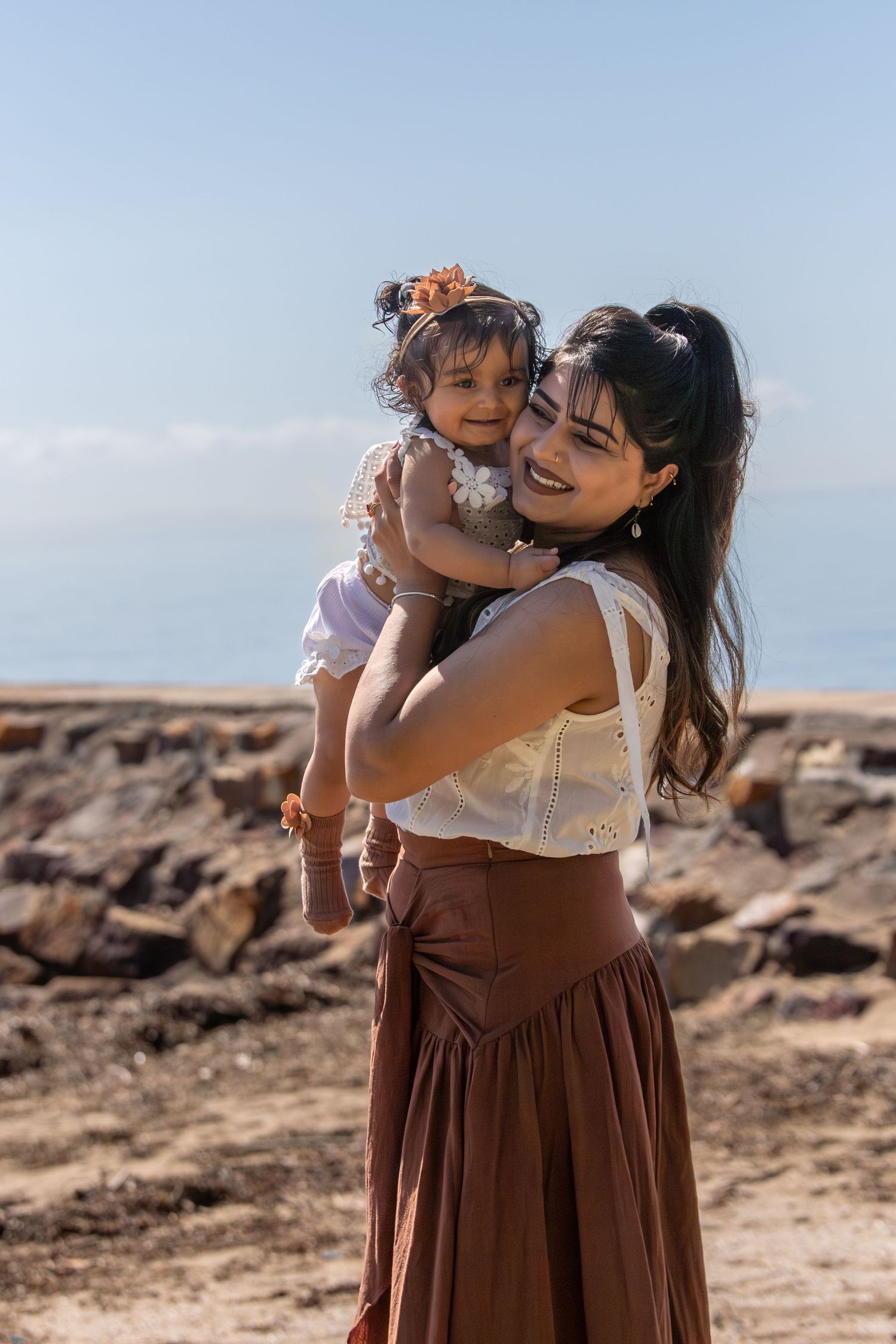 Joyful family embraces captured against scenic coastal backdrop.