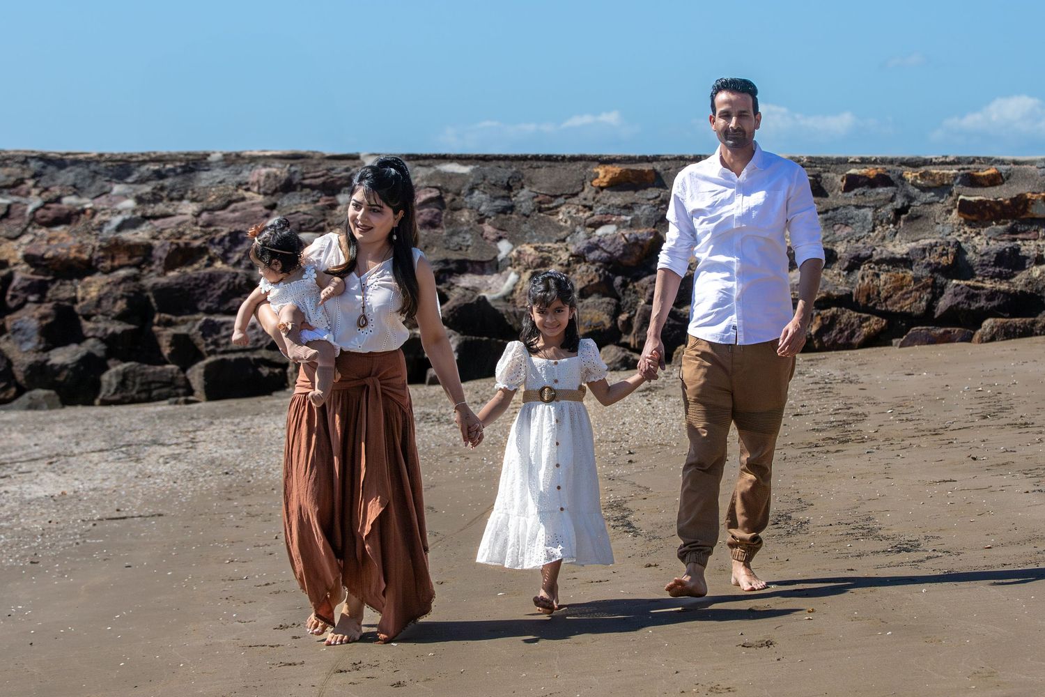 Family members walk hand in hand along a scenic rocky beach.