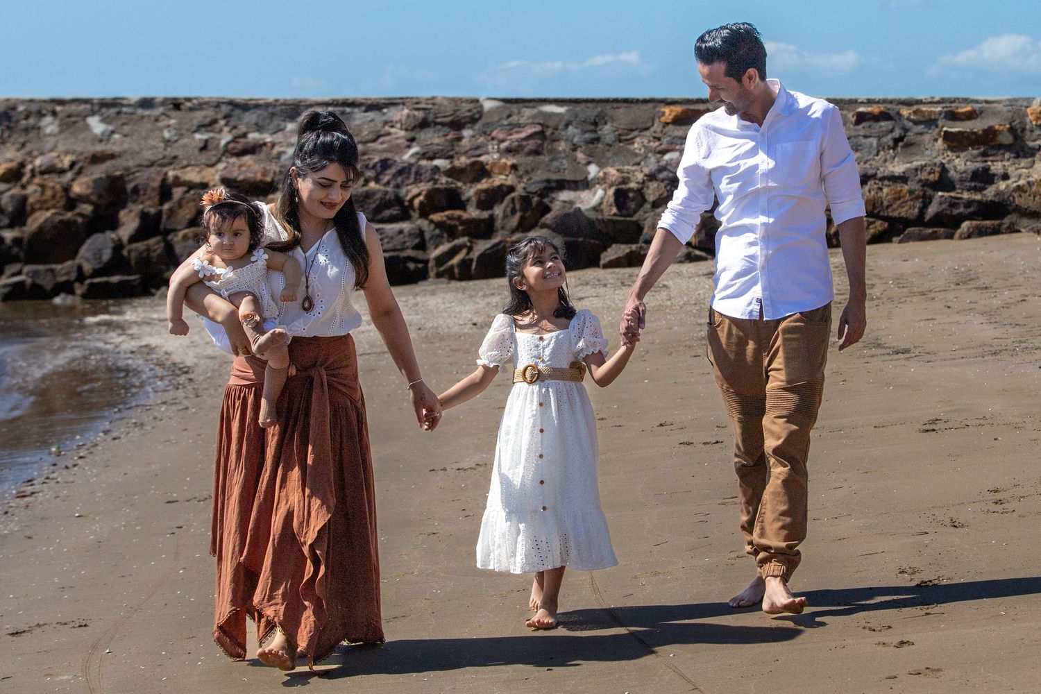 Family members enjoy a beach walk together on a sunny afternoon.