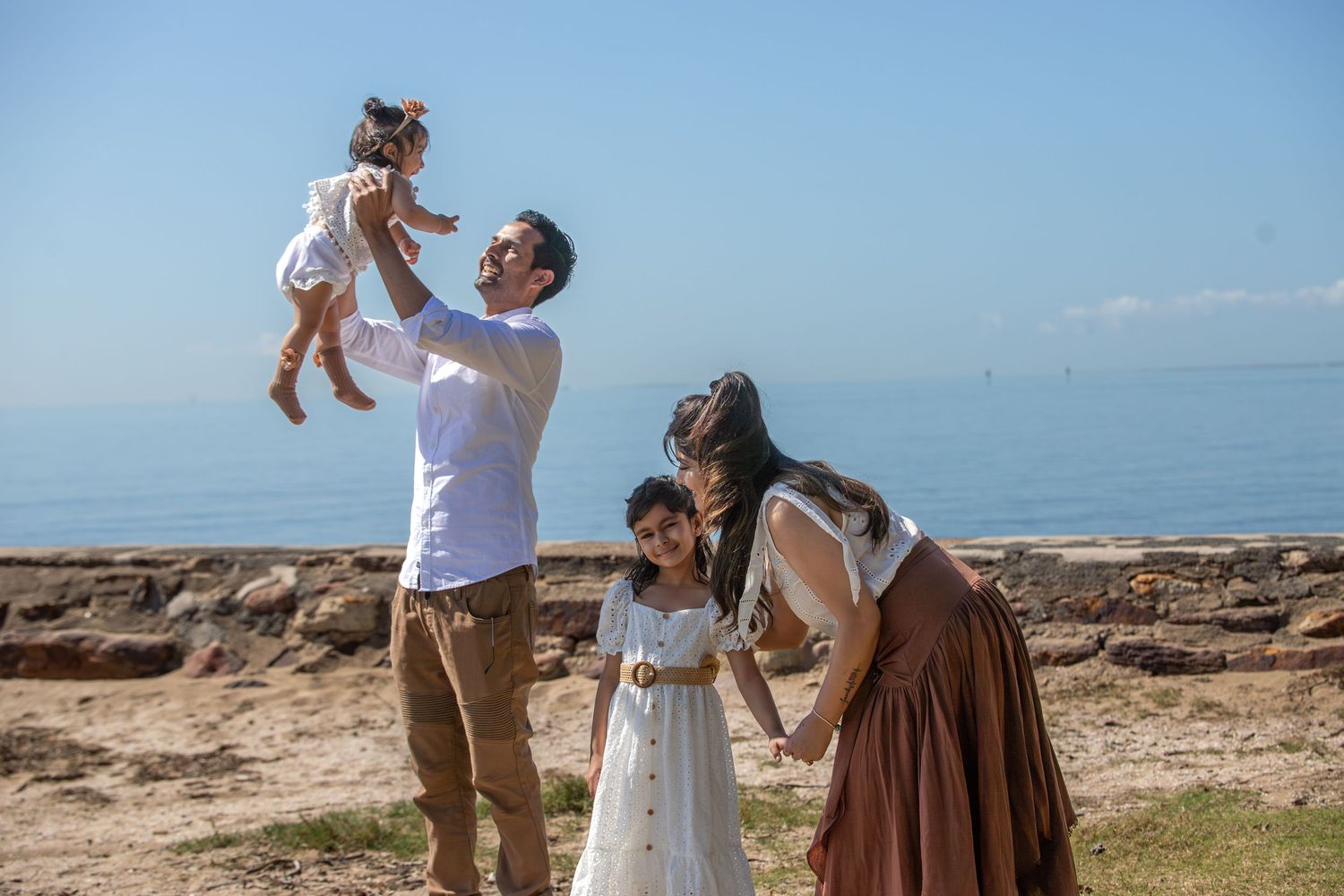 Family sharing joyful moments together by the ocean on a bright sunny day.