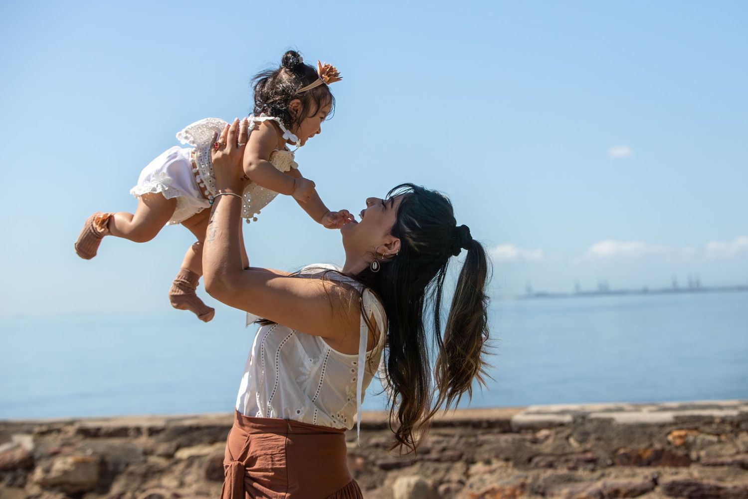 Energetic family playtime captured against coastal landscape and blue sky.