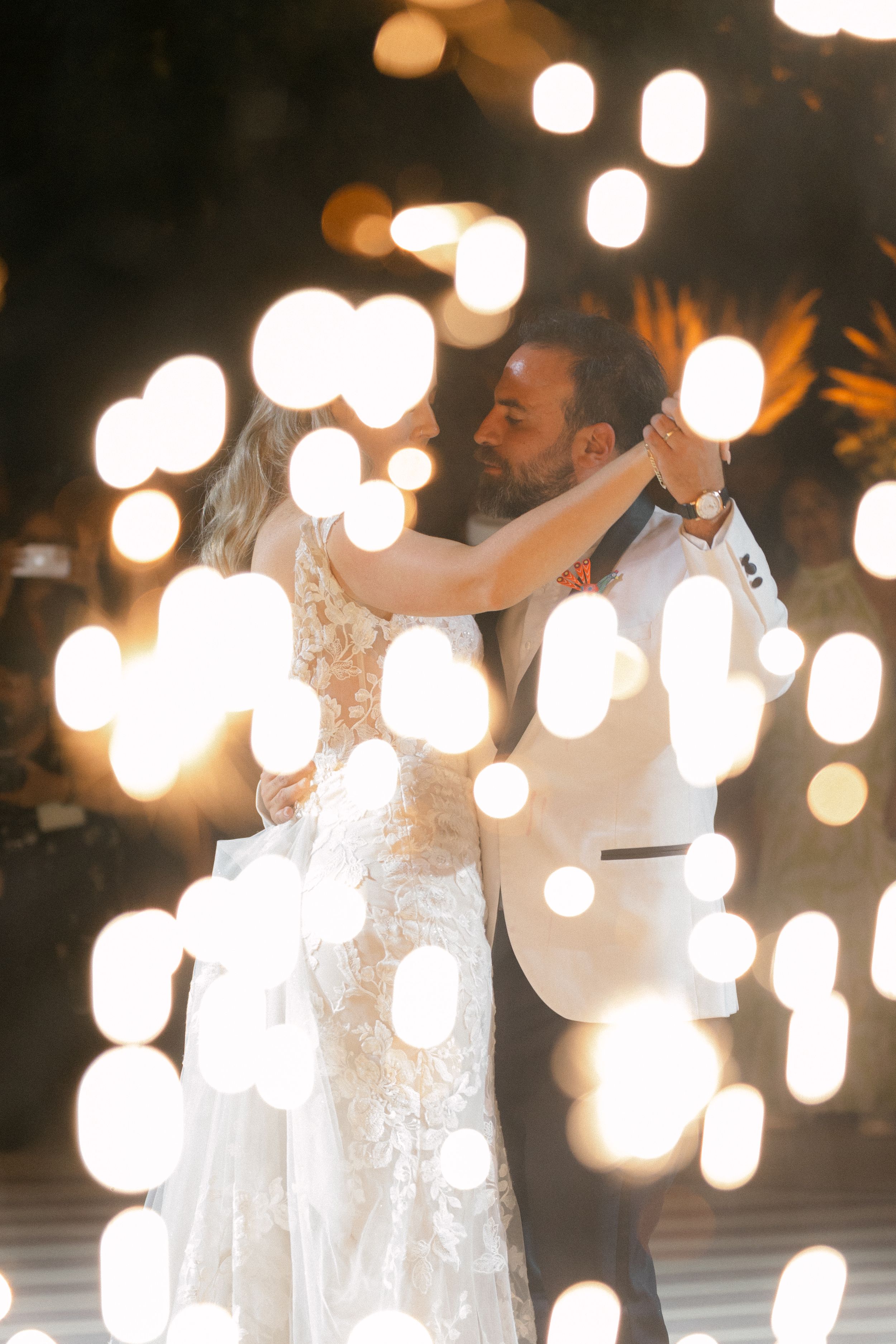 Romantic wedding dance captured at night with glowing bokeh lights creating a dreamy atmosphere by Alejandro Cayetano Photography